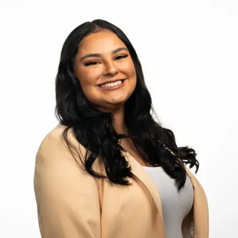 Woman in a white shirt and cream colored jacket smiling at camera
