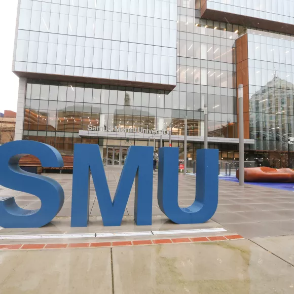 Exterior of the SMU Oakland campus. Large blue "SMU" is in the foreground.