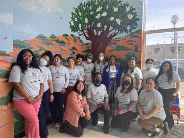15 individuals standing in front of a mural at the Brighter Beginnings clinic.