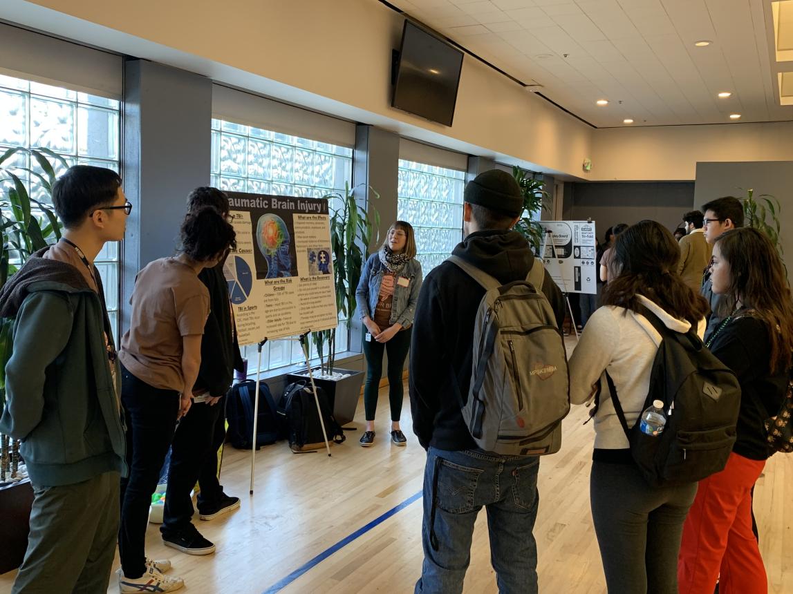 SMU students present poster board on brain function to high school students
