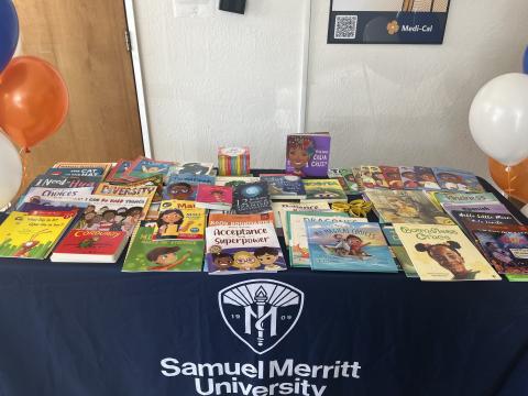 Numerous books on a table with a blue table cloth featuring the SMU logo.