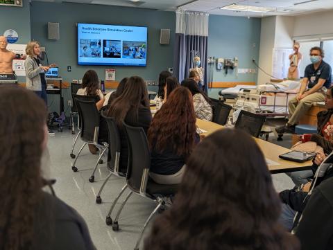 High school students gathered at tables in the Health Science Simulation Center.