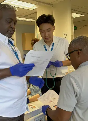 Two prospective students listen to the heart beat of another prospective student in the simulation lab