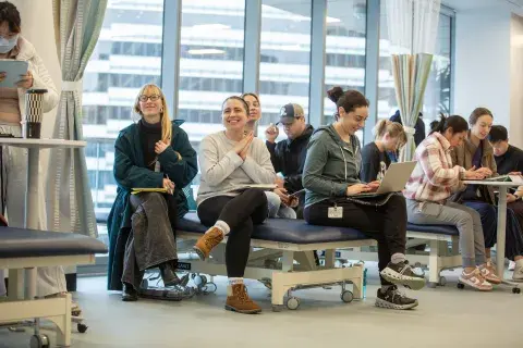 Group of students in sitting in class in the simulation center, smiling.