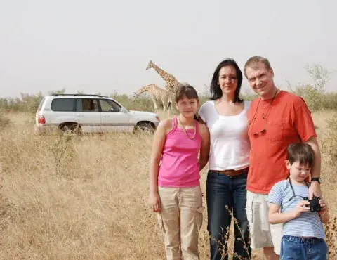 Family of four in African Safari with giraffe in the background