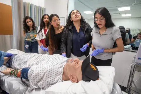 Students around mannequin in simulation center