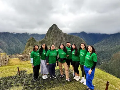 Group of students in Peru posing in front of mountain wearing green t-shirts