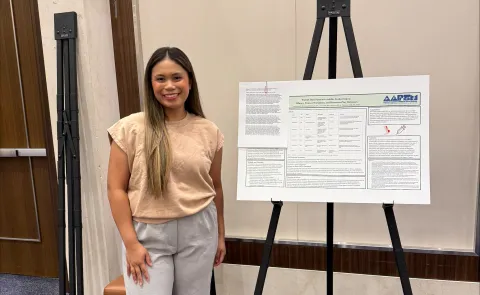 Person standing next to poster board for research presentation
