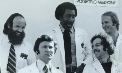 Black and white photo of five men in lab coats