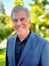 Man in black shirt with blue jacket standing outside