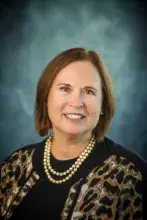 Headshot of woman with shoulder length hair and pearl necklace