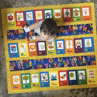 Baby sitting on blanket with alphabet