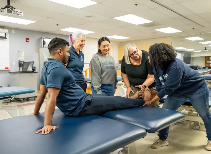 Instructor and Students in Doctor of Physical Therapy Class Examining Patient