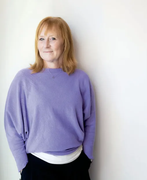 Krista Anderson wearing light purple sweater smiling against a white background.