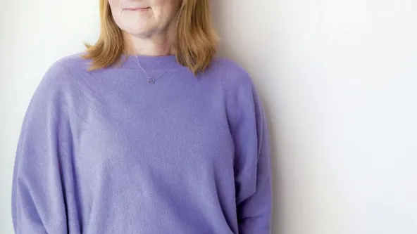 Krista Anderson wearing light purple sweater smiling against a white background.
