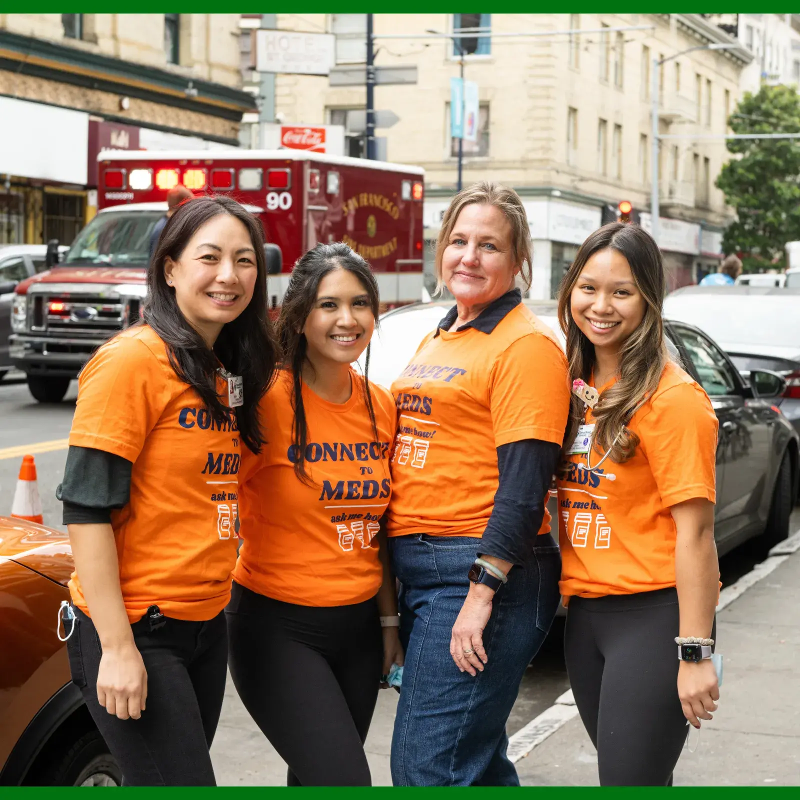 Students and professor standing outside of a clinic with an ambulance in the background