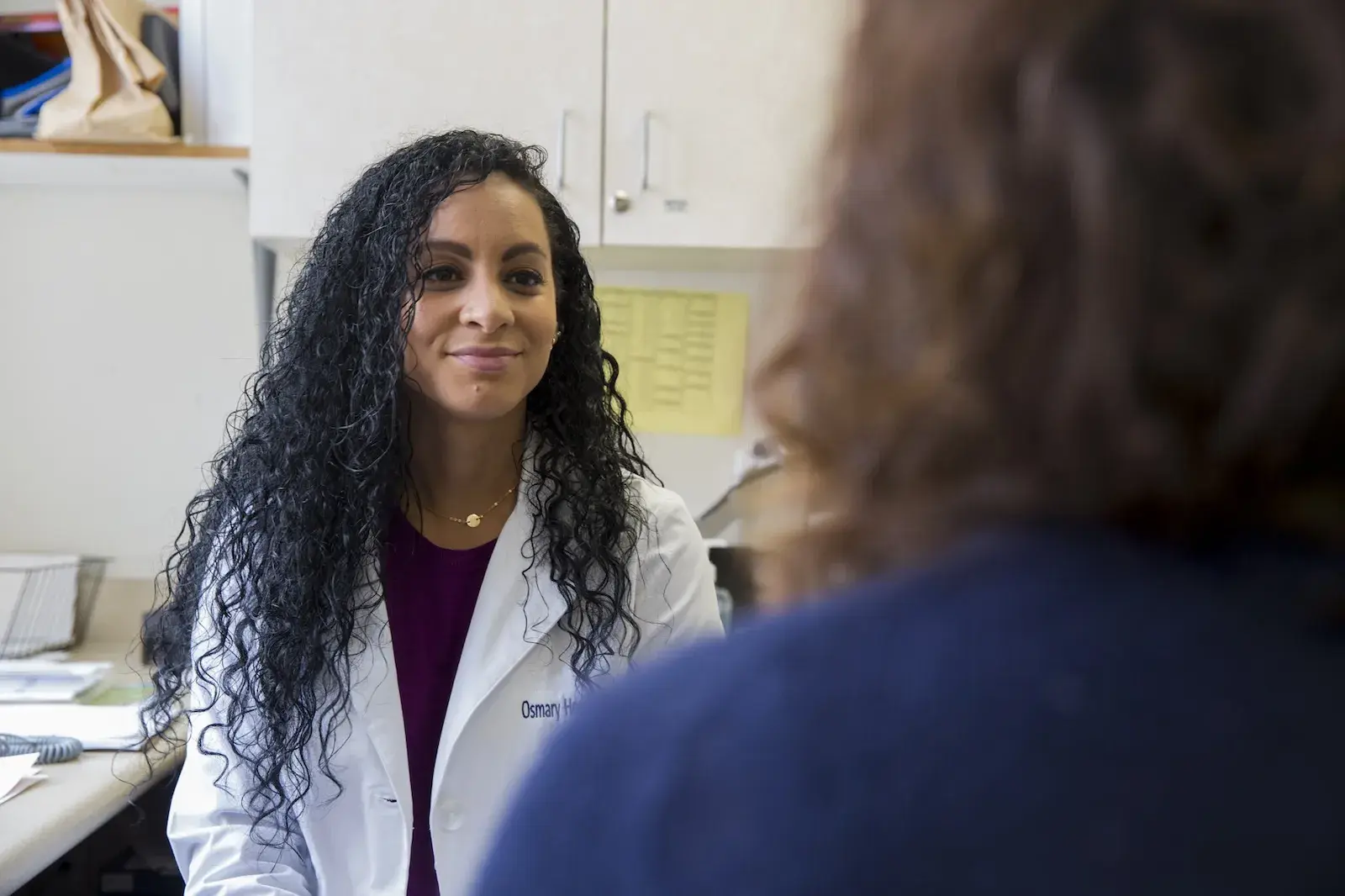 Nurse in white coat listening to a patient