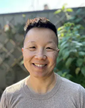 Headshot of person standing outside near a fence