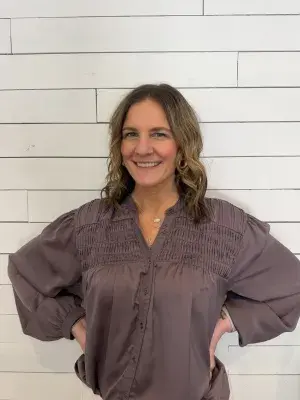 Woman in gray shirt against a white tiled wall