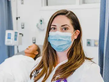 RN to BSN nursing student in simulation lab with manikin behind.