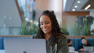 Student in the lobby of SMU Oakland working on a laptop.