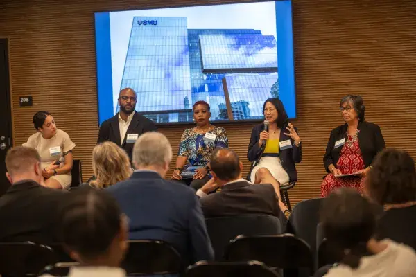 5 panelists on stage, one holds a microphone.