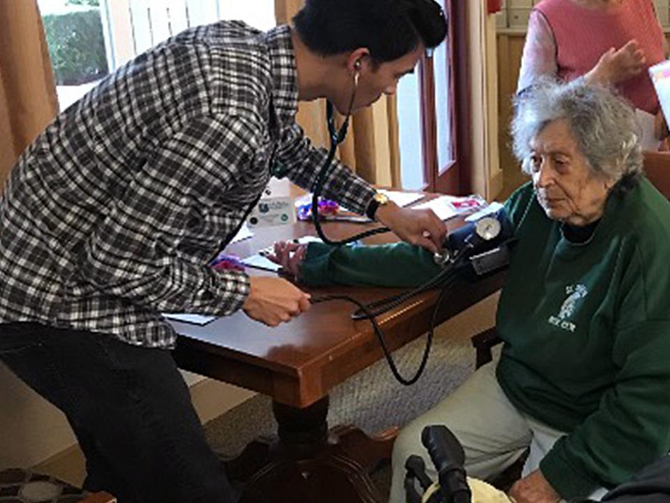 Kevin Pham, BSN '19, takes resident Esfir Kunina's pulse at MidPen Housing in San Mateo
