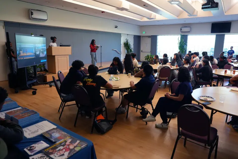 Students gather at round tables to engage in reading session.