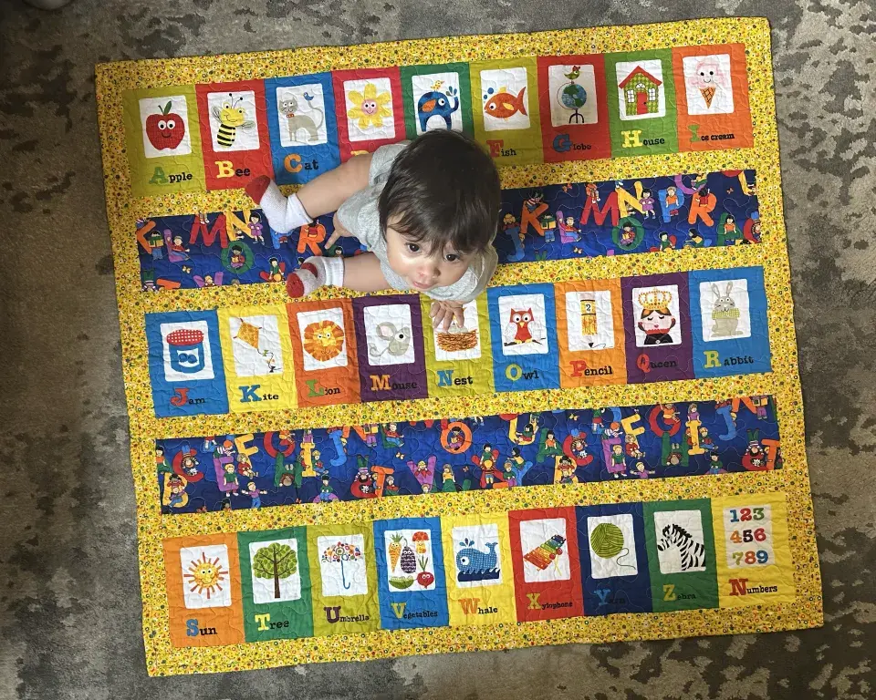 Baby sitting on blanket with alphabet