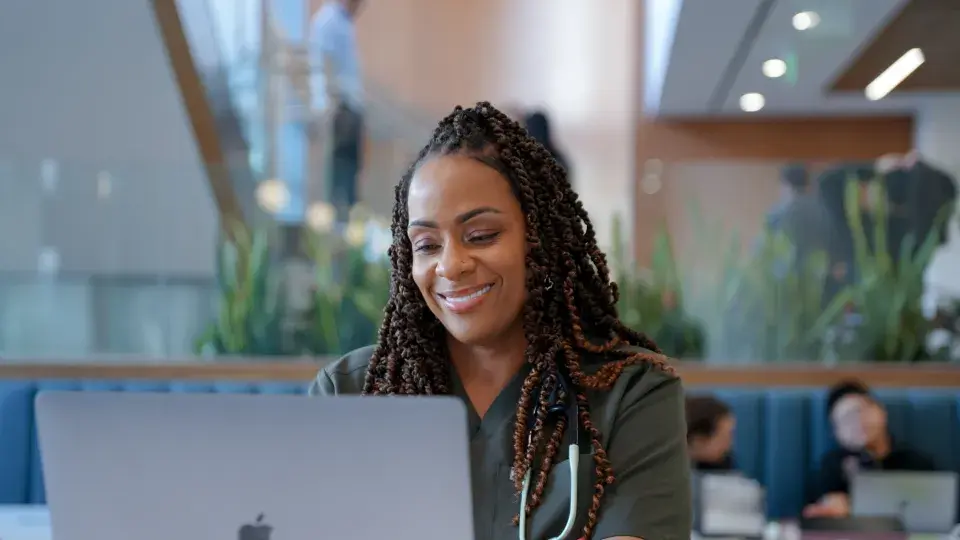 Student in the lobby of SMU Oakland working on a laptop.